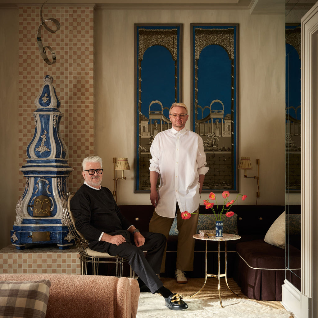 Two men in a stylish living room with decorative elements and artwork.