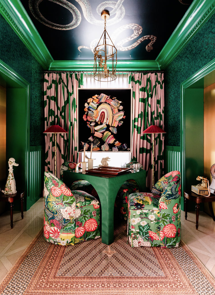 Decorative interior with floral chairs, colorful artwork, and patterned curtains.